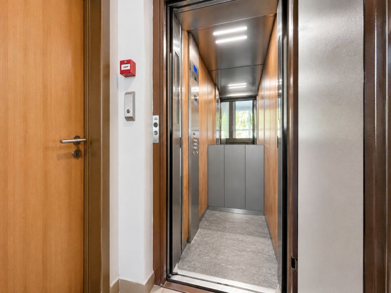 An open elevator and doors in a building, floor with wooden decor.