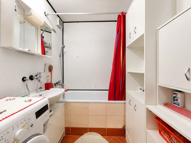 Bathroom with a bathtub, sink, and washing machine, suitable for a studio apartment.