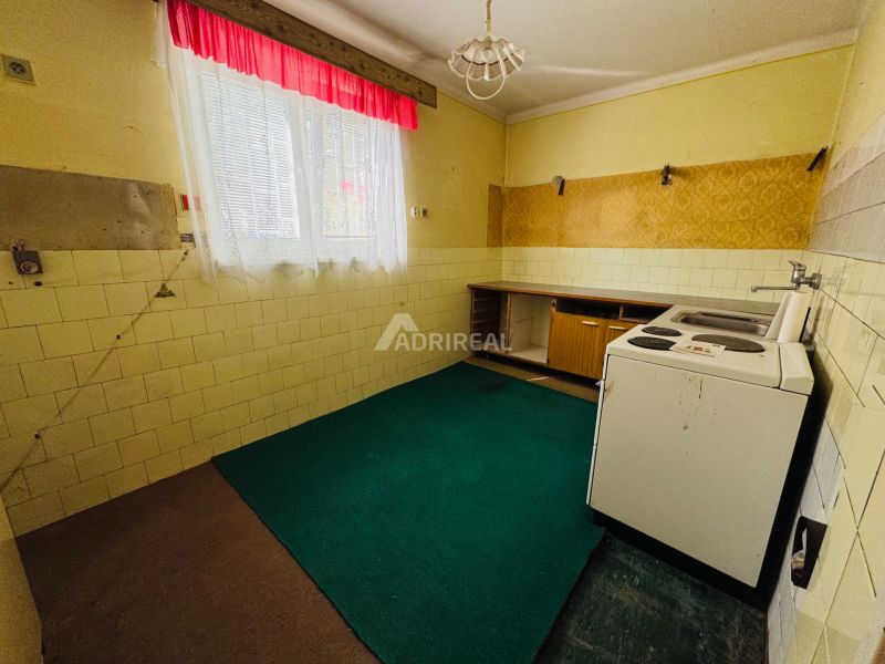 A kitchen in a 2-room apartment with a linoleum floor and a window with curtains.