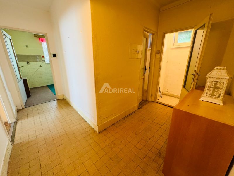Hallway of a 2-room apartment with tiles and several open doors.