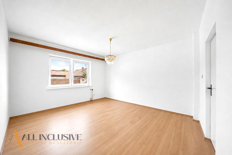 A family house with a wooden decor floor and a chandelier, white walls, large window.