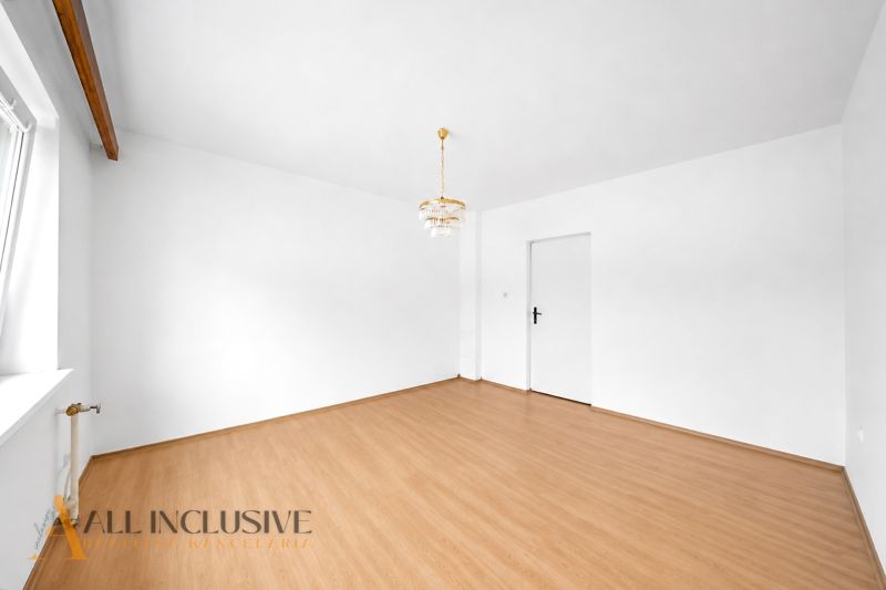 White room in a family house with a wooden decor floor and a chandelier.