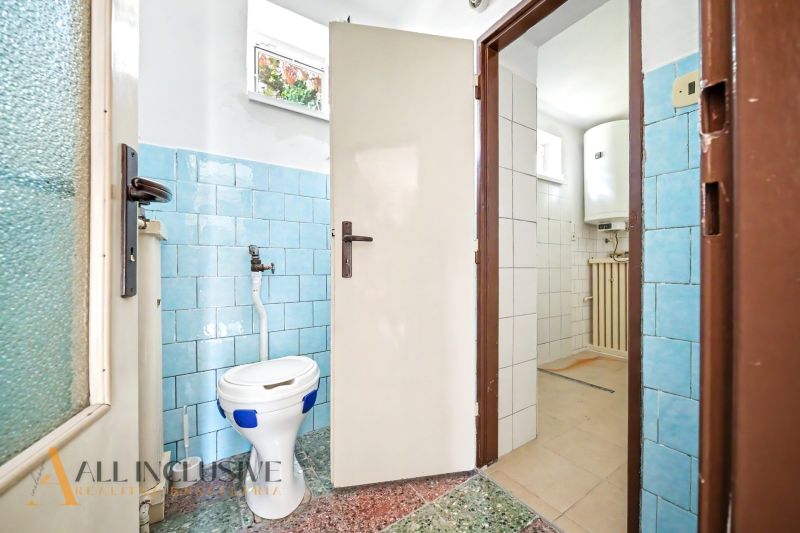A bathroom in a family house with blue tiles and a separate toilet.