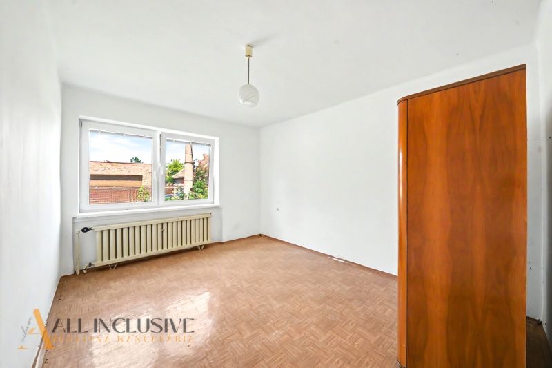 Empty room with a window, wood-patterned floor, and a cabinet in a family house.