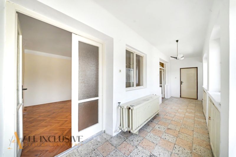 A hallway with a covered floor, a large window, and a door in a family house.