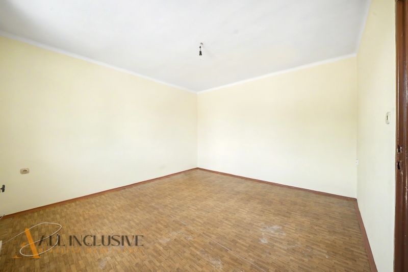 An empty room with wood-patterned flooring and cream walls in a family house.
