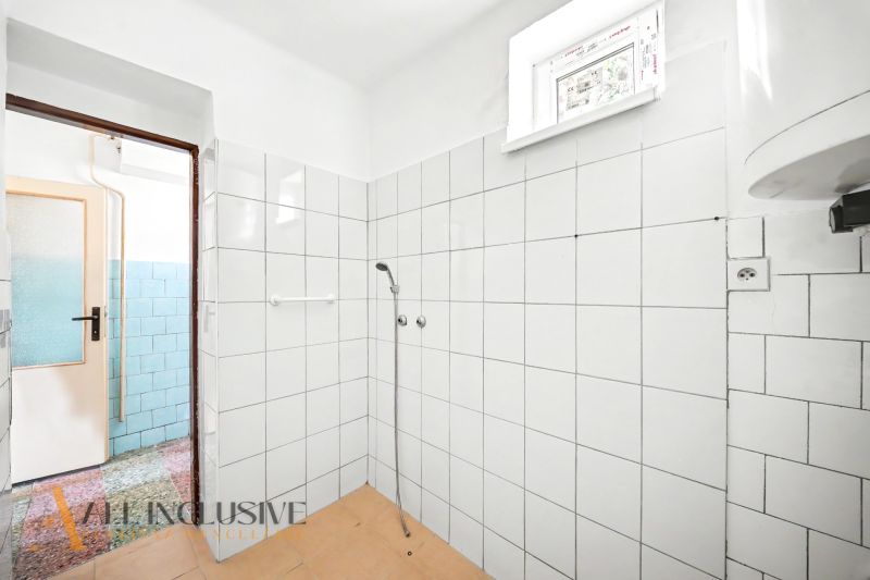 A bathroom in a family house with white tiles and a simple shower.