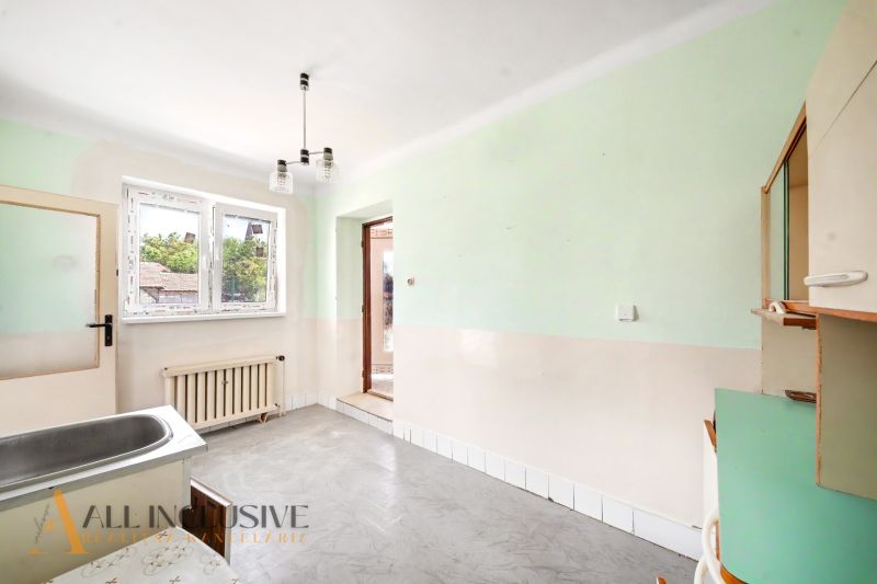 A kitchen area in a family house with a sink, green walls, and a radiator.