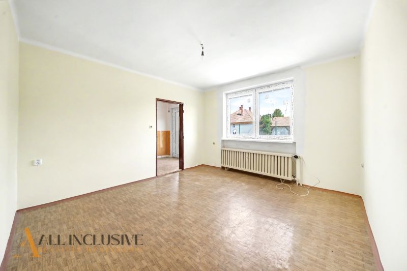 A spacious room with a wooden decor floor and a large window in a family house.