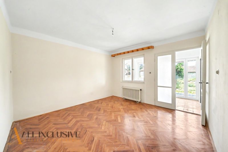 A bright room with a wooden decor floor and a view of the garden in a family house.