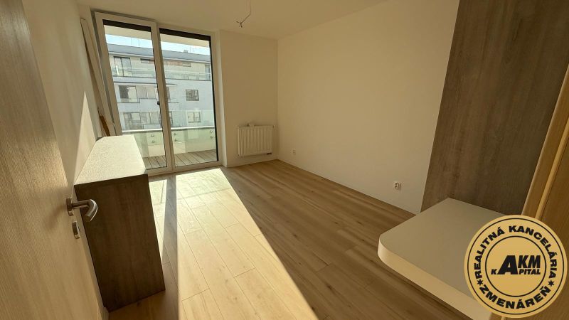A room in a 3-room apartment with a wooden decor floor and large windows.