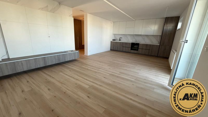 The kitchen area of a 3-room apartment with a wooden decor floor and white cabinets.