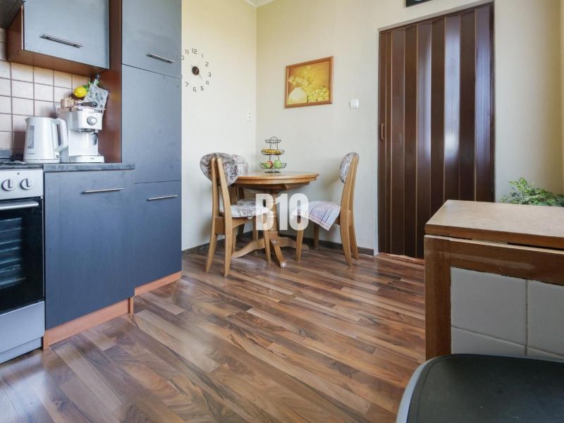 A kitchen corner in a 2-room apartment with a wooden decor floor and a dining table.