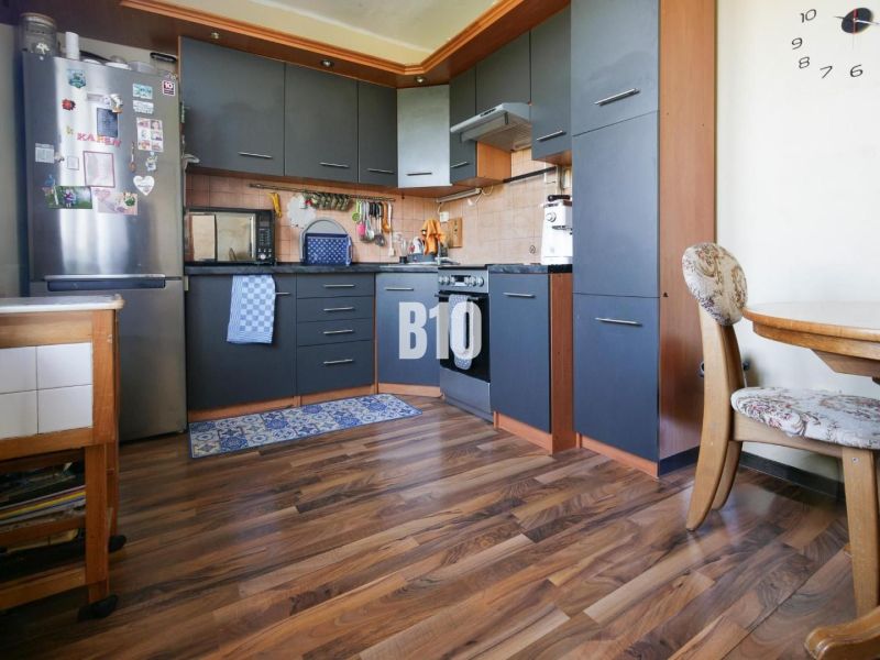 A kitchen in a 2-room apartment with a wood-patterned floor and dark furniture.
