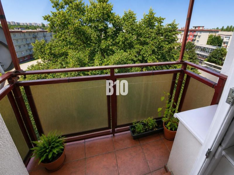 The balcony of a 2-room apartment in Nitra with a view of a greenery-surrounded housing estate.