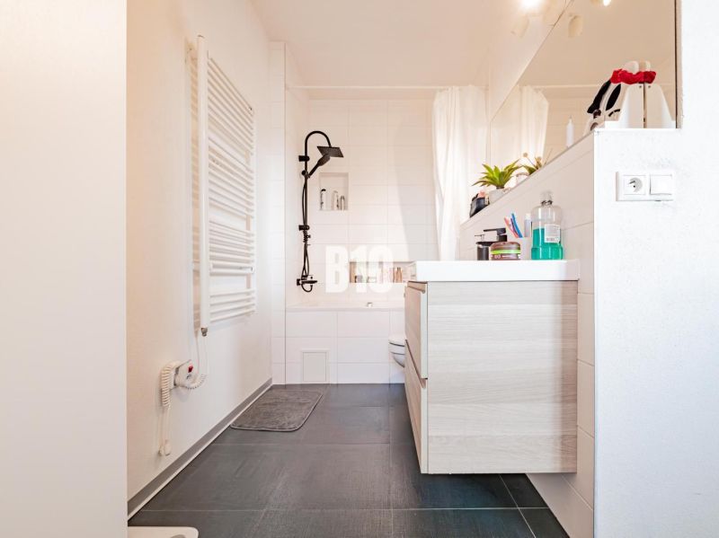 A bathroom in a 3-room apartment with a dark floor and light furniture.