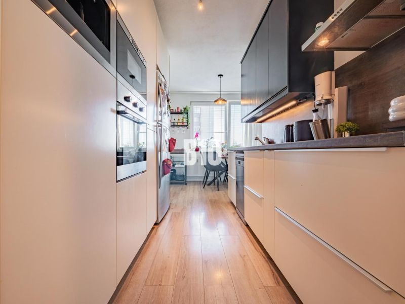 A kitchen in a 3-room apartment with a wooden decor floor and appliances.