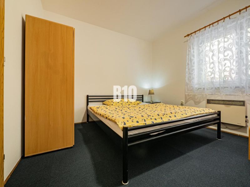 Bedroom in a family house with a metal bed, wardrobe, and patterned curtain.