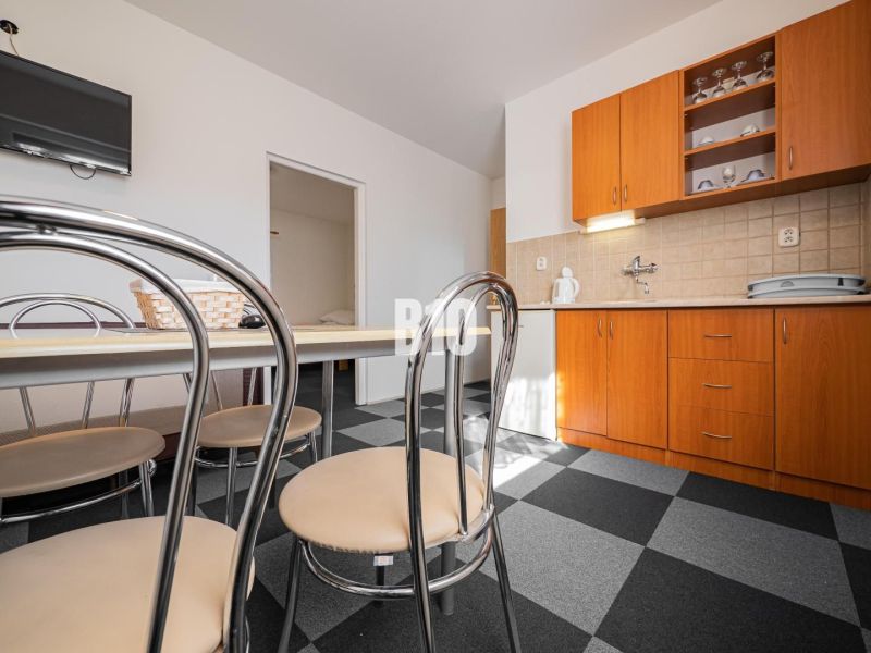 A kitchen in a family house with dark tiles and wooden cabinets.