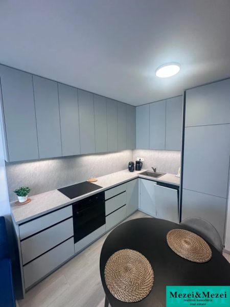 A kitchen in a 2-room apartment with a wooden decor floor and gray cabinets.