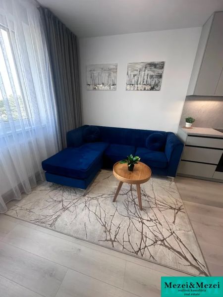 Living room with a blue sofa, table, curtains, and wooden decor flooring.