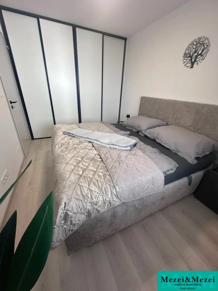 Bedroom in a 2-room apartment with a bed, wardrobe, and wooden decor flooring.