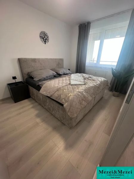 A bedroom in a 2-room apartment with a bed and a wooden decor floor.