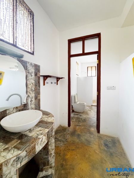 A bathroom in a family house with an interesting mosaic sink countertop and a separate toilet.