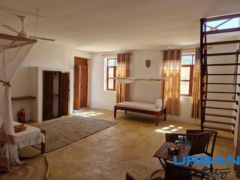 A spacious room with a bed, chairs, and a ladder in a family house.