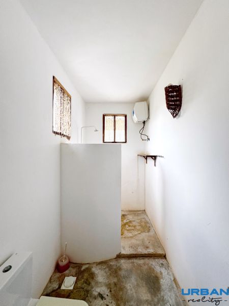 A bathroom in a family house with white walls, a shower corner, and windows.