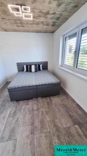 Bedroom with a bed, window, and wooden decor flooring in a family house.