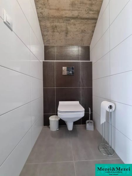 A toilet in a family house with white and brown tiles.