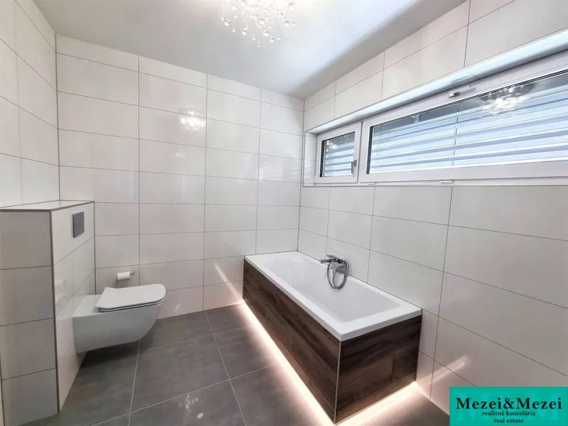 A bathroom in a family house with a wooden decor bathtub and a large window.