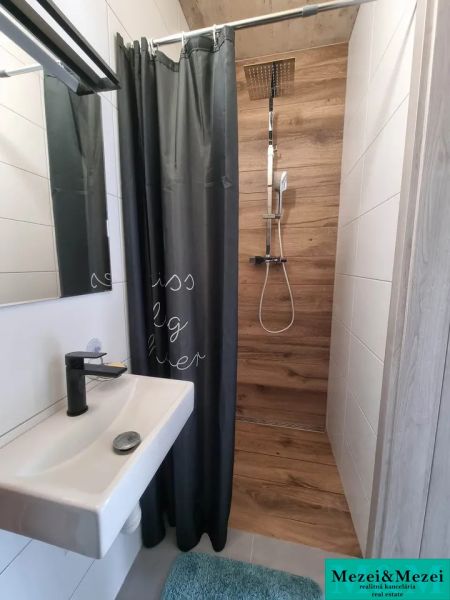 A bathroom in a family house with a wooden decor shower corner and a curtain.