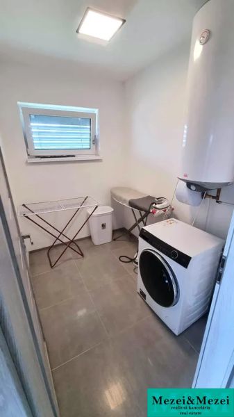 Laundry room in a family house with a washing machine and dryer, floor with wooden decor.