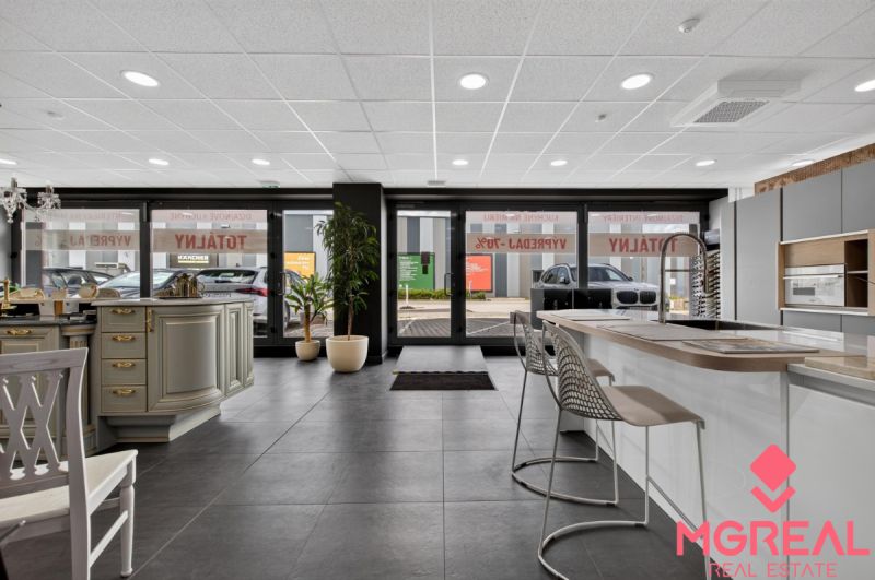 Interior of commercial space with a kitchen counter, bar stools, and large glass doors.