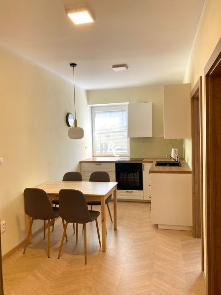 A kitchen with a dining table and a wooden decor floor in a 3-room apartment.