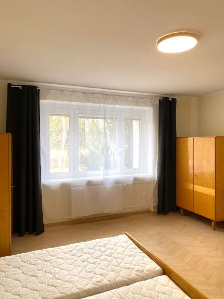 A bright bedroom with a large window and a wooden decor floor in a 3-room apartment.