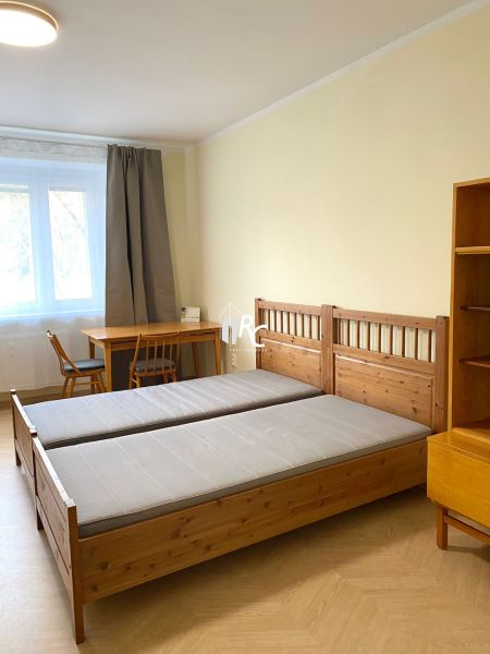 A bedroom with wooden beds, a table, and a floor with a wooden decor in a 3-room apartment.
