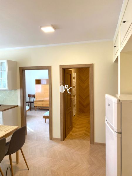 Interior of a 3-room apartment with a wooden decor floor, chairs, and a built-in wardrobe.