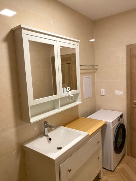 Bathroom in a 3-room apartment with a sink, mirror, and washing machine, ceramic tiles.