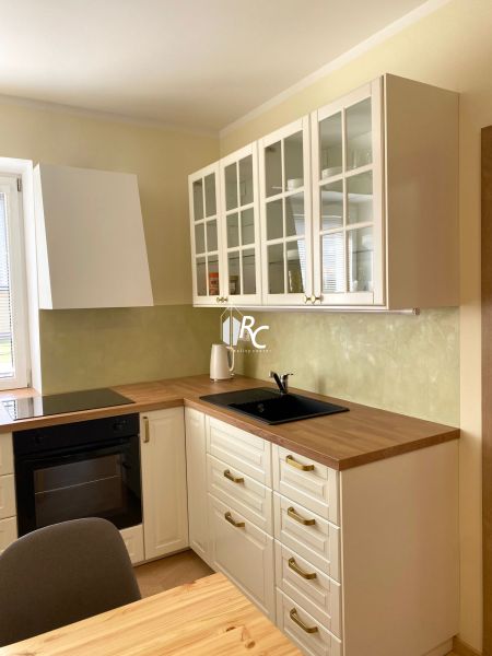 A kitchen in a 3-room apartment with white cabinets and a wood-patterned floor.
