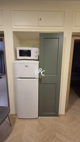 Microwave and refrigerator in the kitchen of a 3-room apartment with a wooden decor floor.