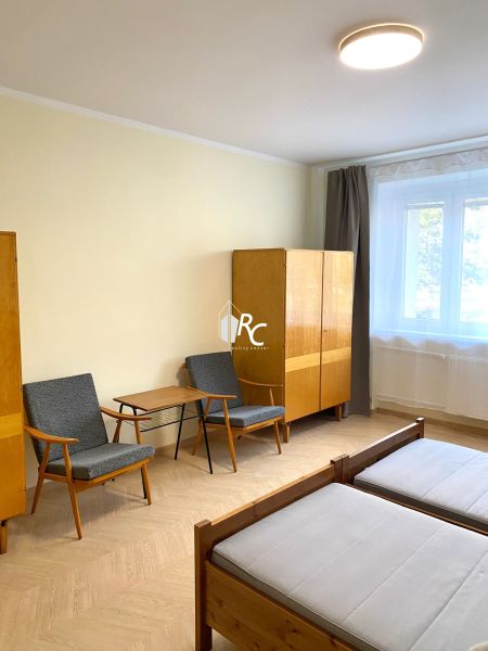 A room in a three-room apartment with a wooden decor floor, two armchairs, and a wardrobe.