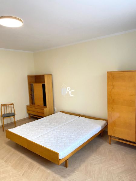 A bedroom with a bed, wardrobe, and wooden decor flooring in a 3-room apartment.
