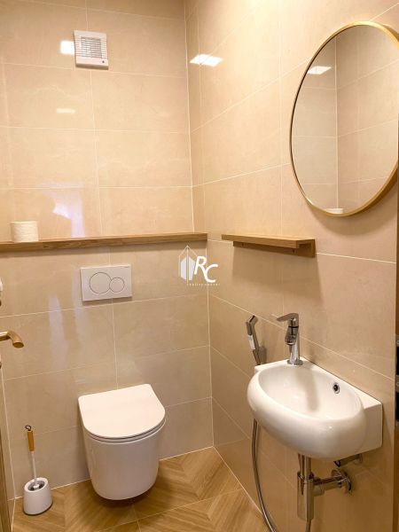 A bathroom in a 3-room apartment with beige tiles and a wooden decor floor.