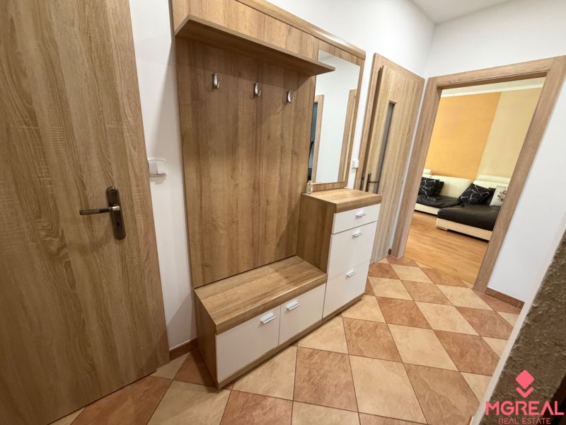 Entrance hall with a mirror and a wardrobe in a 3-room apartment. Floor with wood decor.