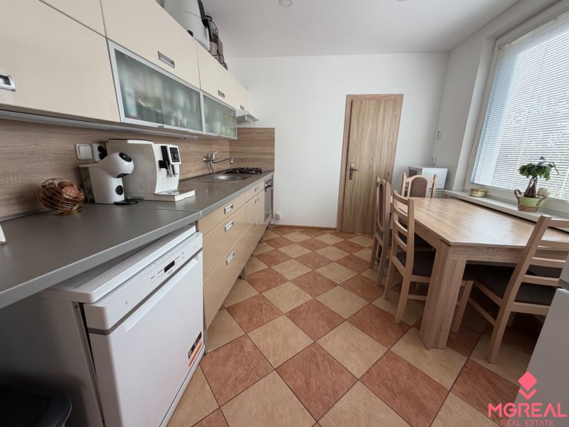 A kitchen in a 3-room apartment with a dining table, kitchen unit, and appliances.