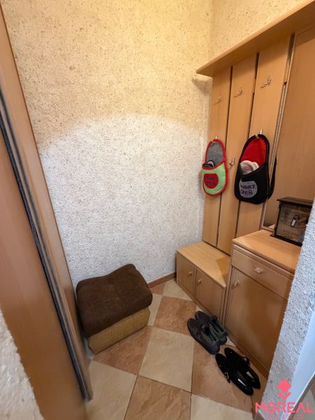 Entrance hall in a 3-room apartment with tiles and a wooden coat rack panel.
