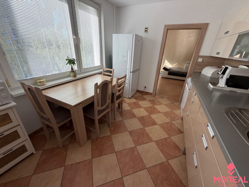 The kitchen in a 3-room apartment with a tiled floor, a dining table, and appliances.